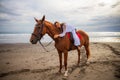 Horsewoman lays down on the withers of the horse. Caucasian woman in white dress riding horse on the beach. Copy space. Sunset
