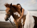 Horsewoman lying on the withers of the horse. Asian woman riding horse on the beach. Homan and animal concept. Bali Royalty Free Stock Photo