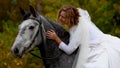 Horsewoman in poofy wedding dress is stroking horse. Close up