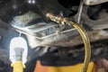 A hose is connected to Oil drain plug of a SUV. For engine oil flush procedure Royalty Free Stock Photo