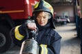 Hose in hands. Female firefighter in protective uniform standing near truck