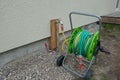 Hose trolley with a rolled-up garden hose on a cold water pipe after installing an outdoor faucet. Royalty Free Stock Photo