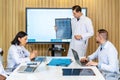 Hospital Conference Meeting Room: Male Physician Presents Patient X-ray on TV Screen, Team of Medical Doctors Discuss Treatment. Royalty Free Stock Photo