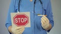 Hospital nurse holding stop sign and a cigarette, preventing unhealthy lifestyle