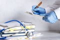 Hospital reseption.Closeup of doctor`s hands, stethoscope and stack of medical histories on the white table