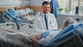 Hospital Ward: Friendly Doctor Talks to Beautiful Senior Female Patient Resting in Bed, Explains Royalty Free Stock Photo