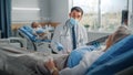 Hospital Ward: Friendly Doctor Wearing Face Mask Talks to Beautiful Senior Female Patient Resting in Royalty Free Stock Photo