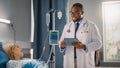 Hospital Ward: Handsome Black Doctor Wearing Glasses Uses Digital Tablet Computer, Checking Patien Royalty Free Stock Photo