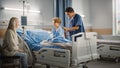 Hospital Ward: Handsome Young Boy Resting in Bed with Caring Mother Supporting Him, Friendly Head Royalty Free Stock Photo