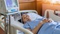 Hospitalized elderly patient senior woman sleeping on bed in hospital ward room with iv medical infusion pump