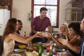 Host and friends pass food round the table at a dinner party Royalty Free Stock Photo