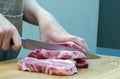 The hostess in the kitchen cuts pork with a knife, prepares food. On a cutting board, spices, chili peppers,garlic, cherry Royalty Free Stock Photo