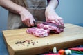 The hostess in the kitchen cuts pork with a knife, prepares food. On a cutting board, spices, chili peppers, rosemary, garlic, Royalty Free Stock Photo