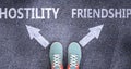 Hostility and friendship as different choices in life - pictured as words Hostility, friendship on a road to symbolize making