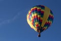 A hot air balloon is ascending into the blue sky