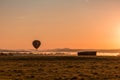 Hot air balloon is basked in a golden glow as it slowly ascends over a fog-filled valley on an early fall mo