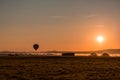 Hot air balloon is basked in a golden glow as it slowly ascends over a fog-filled valley on an early fall mo