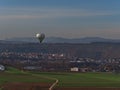 Hot air balloon branded by utility company Stadtwerke Stuttgart flying at low altitude above fields in autumn near Besigheim.