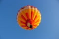 Hot air balloon in clear sky, bottom view. Colorful balloon on blue background. Bright geometric design.