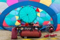 A hot air balloon is filling in preparation for take off with the equipment laid out and ready on a bench