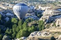 A hot air balloon flies down Love Valley at sunrise near Goreme in the Cappadocia region of Turkey.