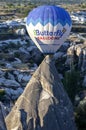 A hot air balloon flies past a fairy chimney at sunrise near Goreme in the Cappadocia region of Turkey.