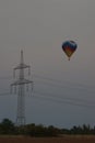 Hot air balloon floating at sunset past some power lines in the evening sky Royalty Free Stock Photo