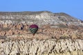 A hot air balloon floats above the unique Cappadocia landscape.