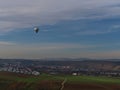 Hot air balloon flying at low altitude above agricultural fields near village Besigheim with Neckar river valley.
