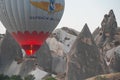 Hot air balloon flying next to fairy chimneys cave houses in Cappadocia Royalty Free Stock Photo