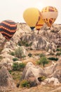 Hot air balloon flying over Cappadocia mountain landscape at gold sunrise Royalty Free Stock Photo