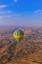 Hot air balloon flying over rocky landscape at sunrise - Cappadocia Turkey Royalty Free Stock Photo