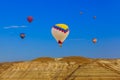 Hot air balloon flying over rocky landscape at sunrise - Cappadocia Turkey Royalty Free Stock Photo