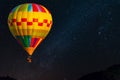 Hot air balloon flying over spectacular under the sky with  and shininng star at night Royalty Free Stock Photo