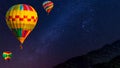 Hot air balloon flying over spectacular under the sky with and shininng star at night Royalty Free Stock Photo