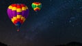 Hot air balloon flying over spectacular under the sky with and shininng star at night Royalty Free Stock Photo