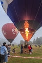 Hot air balloon lit up by burst of flame from burner