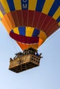 A hot air balloon loaded with tourists floats above Goreme in Turkey at sunrise.