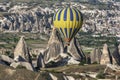 A hot air balloon navigates past fairy chimneys near goreme in Turkey. Royalty Free Stock Photo