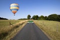 Hot air balloon over single lane country road
