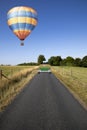 Hot air balloon over single lane country road Royalty Free Stock Photo