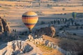 Hot air balloon with rainbow colors pattern rising over the Cappadocian valley