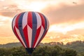 Hot air balloon in red, white and blue floats among the mountains in a beautiful sky at dusk Royalty Free Stock Photo