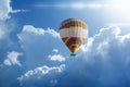 Hot air balloon rises very high in blue sky above white clouds Royalty Free Stock Photo