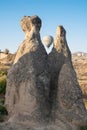 Hot air balloon rising behind two rock chimneys in Cappadocia