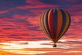 A hot air balloon rising under partly cloudy skies during a brillant sunset