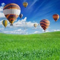 Hot air ballooning above green field Royalty Free Stock Photo