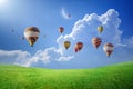 Hot air balloons flying in blue sky above green field Royalty Free Stock Photo