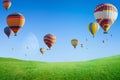 Hot air balloons flying in clear blue sky above green grass fiel Royalty Free Stock Photo