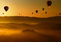 Hot air balloons flying at dawn above the misty hills in Tuscany Royalty Free Stock Photo